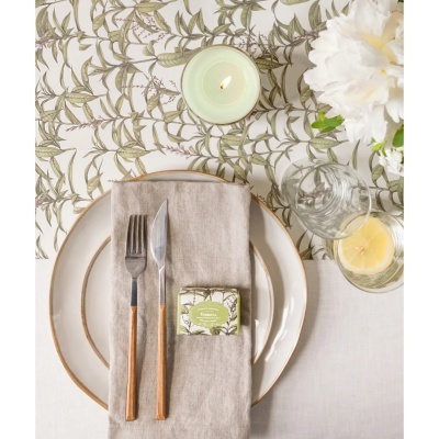 Conjunto de mesa com prato branco dourado, guardanapo de linho, talheres de madeira, vela acesa, copo com limão e sabonete Verbena
