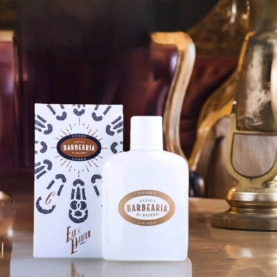 Frasco branco e caixa de perfume Antiga Barbearia de Bairro Chiado sobre superfície refletora