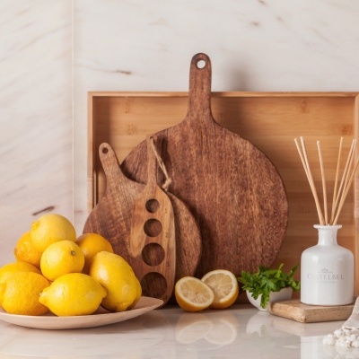 Tábuas de madeira com limões, prato e difusor branco em bancada de cozinha