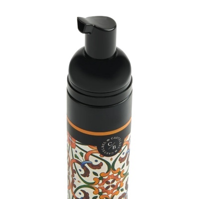 Frasco dispensador preto com padrão floral colorido e selo preto de marca