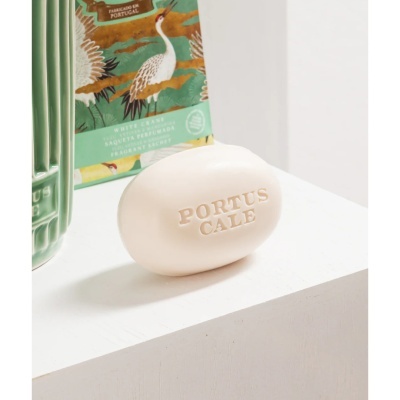 Sabonete branco oval com gravação PORTUS CALE e embalagem verde com ilustração de aves