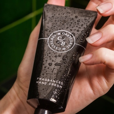 Bisnaga preta de creme de mãos com gotas de água e texto branco