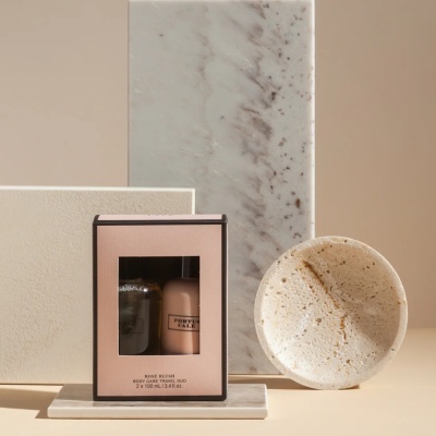 Conjunto de cuidados para o corpo Rosé Blush em caixa cor-de-rosa com dois frascos visíveis, numa configuração de mármore e pedra natural