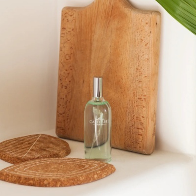 Frasco de vidro transparente com líquido e texto CASTELBEL PORTO, bases de cortiça e tábua de madeira