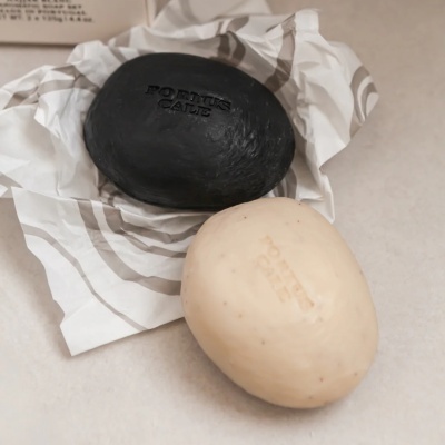 Sabonetes pretos e bege ovais com gravação PORTUS CALE em papel riscado.