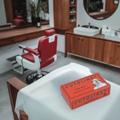 Caixa vermelha de Cutoline After Shave sobre toalha branca numa barbearia