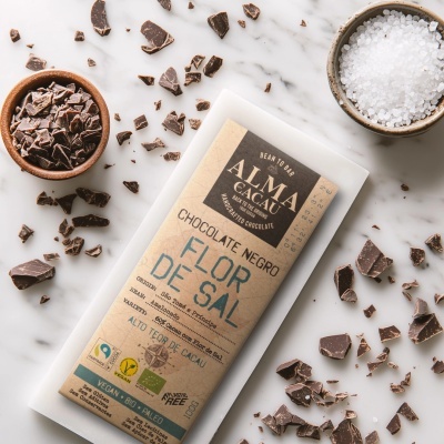 Barra de chocolate negro ALMA CACAU com Flor de Sal e pedaços de chocolate em fundo marmoreado com tigela de sal grosso