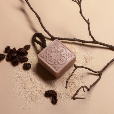 Sabonete quadrado rosa com padrão e cordão preto com ramos secos e frutos secos