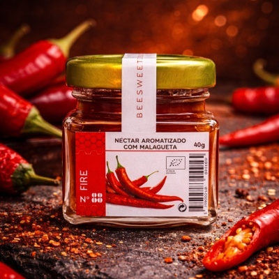 Frasco de néctar aromatizado com malagueta rodeado por malaguetas frescas