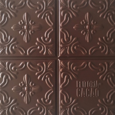 Quadrados de chocolate preto com arabescos e texto em relevo LETORIA CACAO