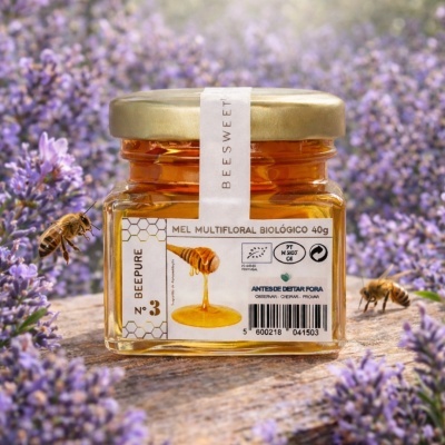 Frasco de mel multifloral biológico de 40g com tampa dourada e etiqueta branca, rodeado por flores roxas e abelhas