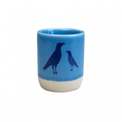 Copo cerâmico azul com aves pretas e base branca.
