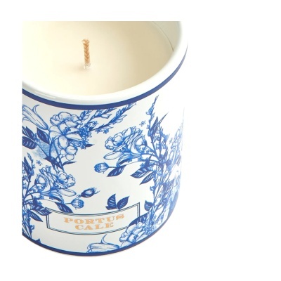 Vela branca em recipiente cerâmico azul e branco com padrão floral e texto PORTUS CALE