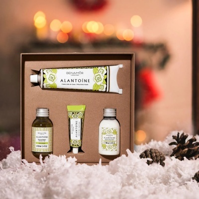 Conjunto de produtos de beleza Benamôr Alantoíne em caixa castanha com neve artificial e pinhas ao redor