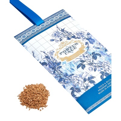 Saco perfumado branco e azul com padrão floral e texto, com fita azul e monte de grãos castanhos