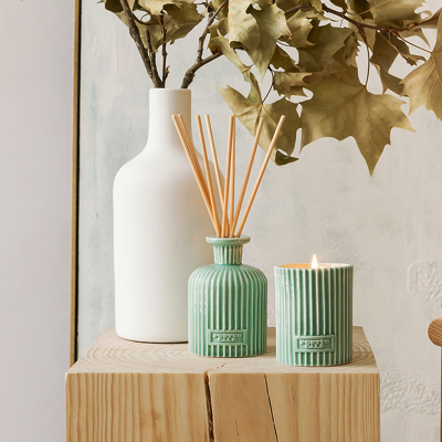 Conjunto de difusor e vela verde em cerâmica com textura e vaso branco ao fundo