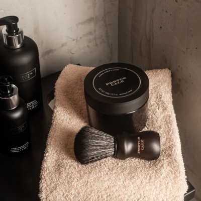 Produtos de barbear Portus Cale em embalagem preta com pincel sobre toalha bege