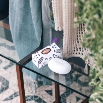 Sabonete branco com embalagem decorada sobre mesa de vidro