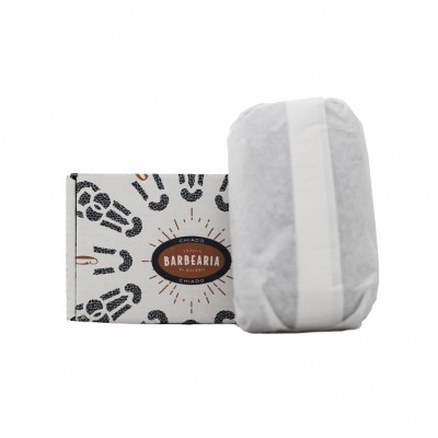 Caixa de sabonete branca com padrões de pegadas e barra de sabonete embrulhada ao lado