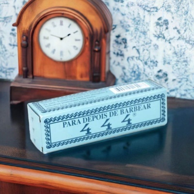 Caixa azul claro com texto PARA DEPOIS DE BARBEAR 444 em superfície espelhada com relógio de madeira ao fundo