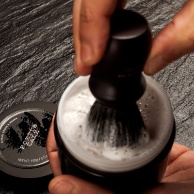 Creme de barbear Porto Cale com escova fazendo espuma sobre fundo cinza