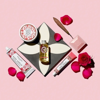 Produtos cosméticos Benamôr Rose Amélie com creme, óleo, sabonete, creme e pétalas de rosa