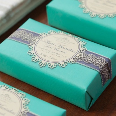 Sabonete aromático embalado em papel azul com faixa roxa e etiqueta circular decorativa
