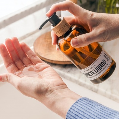 Frasco âmbar com sabonete líquido a ser aplicado na mão