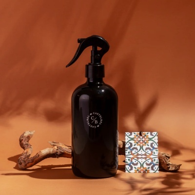 Frasco negro com pulverizador e cartão decorativo com padrões