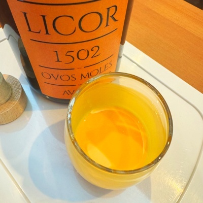 Frasco de licor com rótulo laranja e copo com licor amarelo