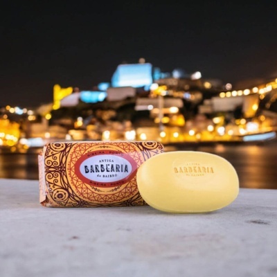 Sabonete amarelo oval com embalagem decorativa castanha e texto ANTIGA BARBEARIA de BAIRRO