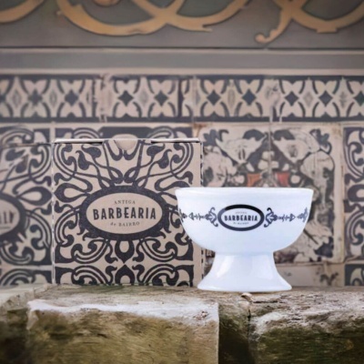 Taça branca decorada com motivo preto e caixa com padrão de azulejos atrás