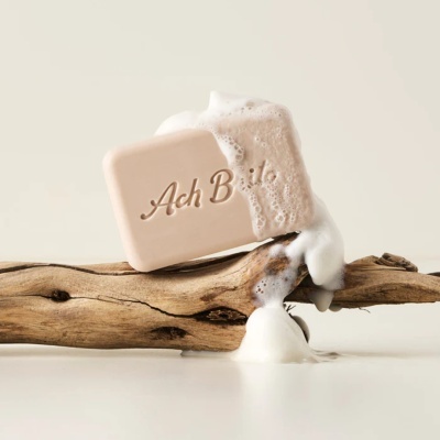 Sabonete bege com espuma sobre madeira rústica
