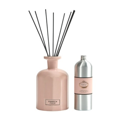 Frasco difusor de fragrância cor de rosa claro com varetas pretas e frasco metálico.