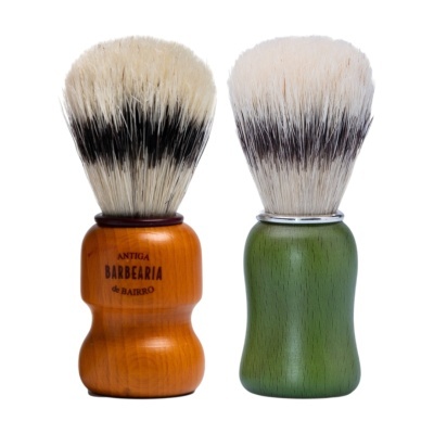 Dois pincéis de barbear com cerdas brancas e pretas, um com cabo de madeira laranja com texto e outro com cabo verde e anel metálico