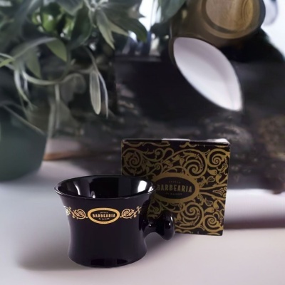 Copo para barbear preto com detalhes dourados e caixa decorada ao fundo