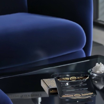 Placa preta decorativa com texto BARBERARO em mesa de vidro junto a cadeira azul