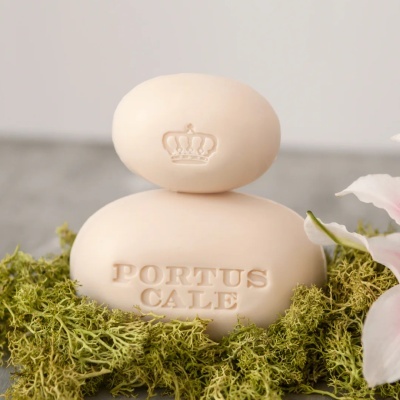 Duas sabonetes bege com gravações, sobre musgo e flor