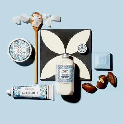 Produtos de cuidado corporal GORDISSIMO com embalagem azul e branca e sabonete azul sobre fundo azul claro