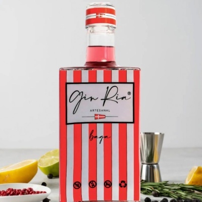Garrafa de gin artesanal Gin Ria com listras vermelhas e brancas e ingredientes ao redor
