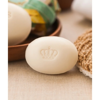 Sabonete branco oval com uma coroa em relevo numa superfície de tecido bege