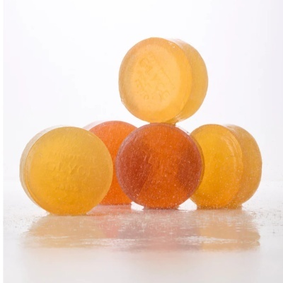 Pastilhas redondas translúcidas amarelas e laranja sobre superfície branca