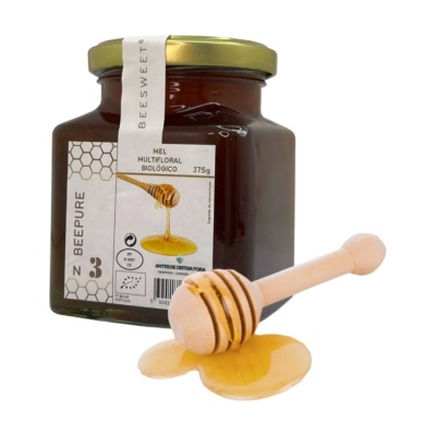 Frasco de mel multifloral biológico BEEPURE com colher de madeira e mel derramado.