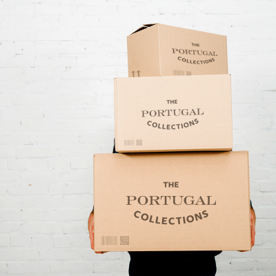 Caixas de cartão 'THE PORTUGAL COLLECTIONS' empilhadas contra parede branca.