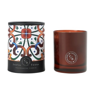 Vela perfumada Santal Tonka em copo de vidro castanho ao lado da embalagem decorada