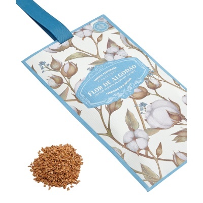 Saqueta perfumada floral azul e branca com fita azul e partículas marrons num fundo branco