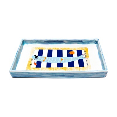 Tabuleiro de cerâmica com figura de peixe azul sobre fundo listrado azul e branco