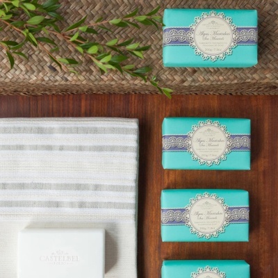 Sabonetes embalados e sabonete branco sobre toalha e superfície de madeira com decoração natural