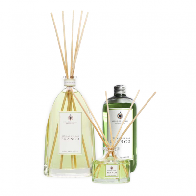 Difusores de aromas com varetas de madeira em frascos de vidro com líquidos verde e transparente.