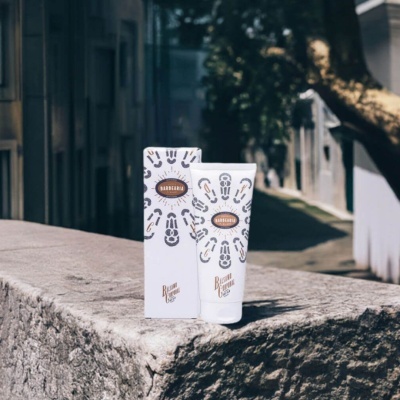 Creme em tubo branco e caixa com padronagem e logótipo BARBEARIA e BALZANO CAMPANA sobre pedra